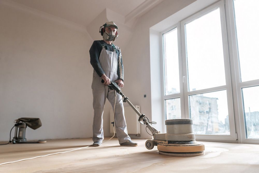 A Man is Polishing a Wooden Floor With a Machine — Coastline Floor Sanding in Gosford, NSW