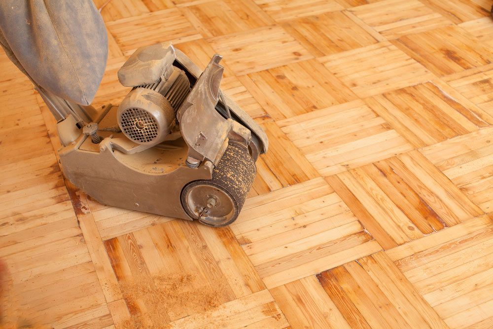 A Person is Sanding a Wooden Floor With a Machine — Coastline Floor Sanding in Wyong, NSW