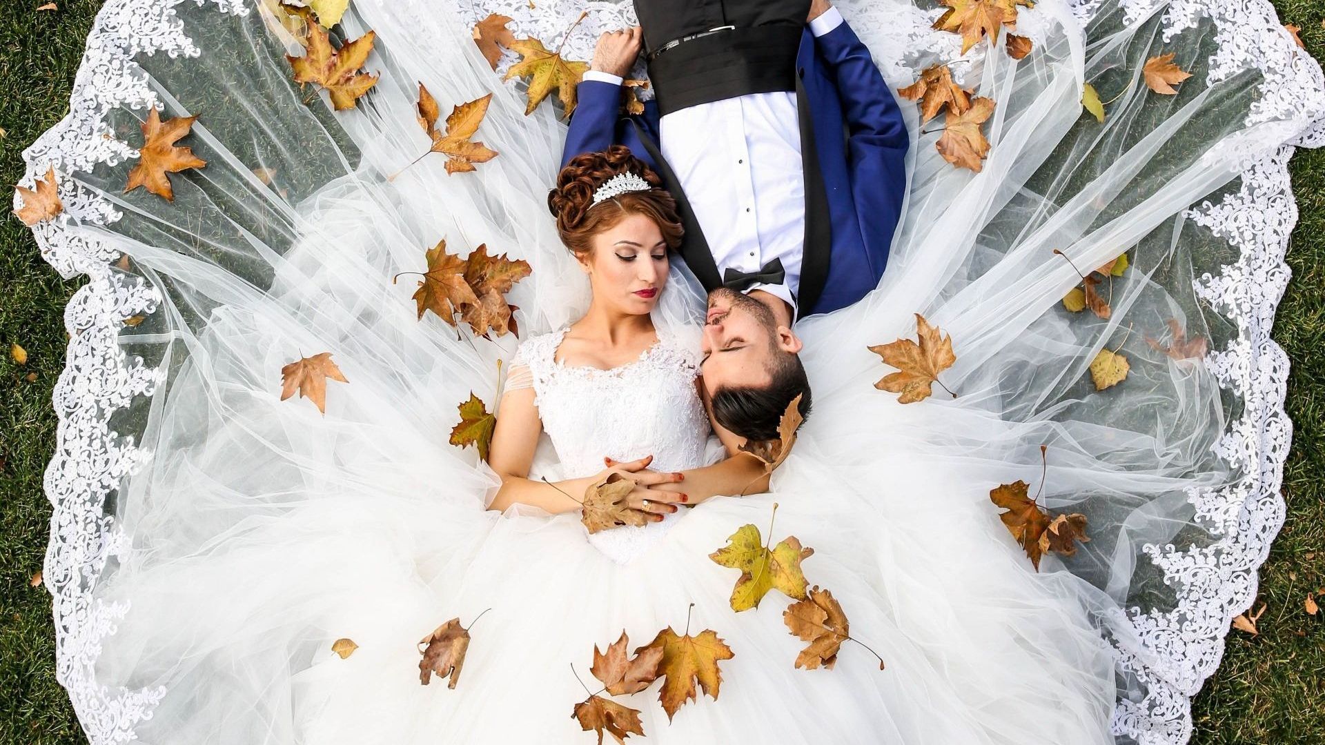 bride and groom lay on grass to pose for wedding photos with a Charlotte wedding photographer