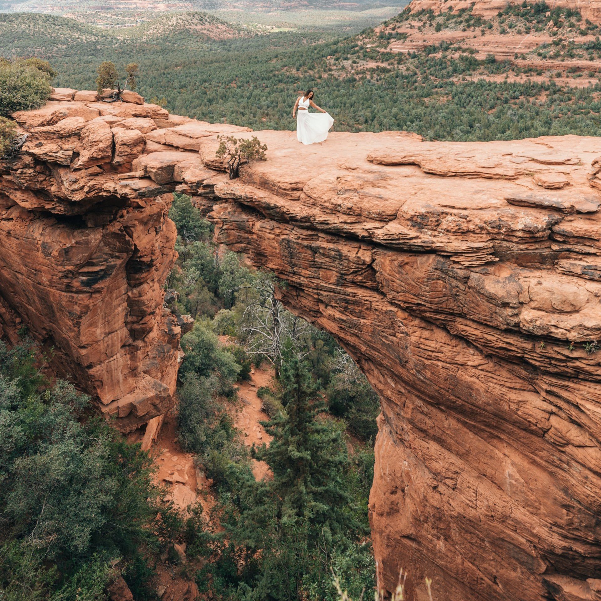 aerial photo of bride in wedding dress at the top of a high cliff