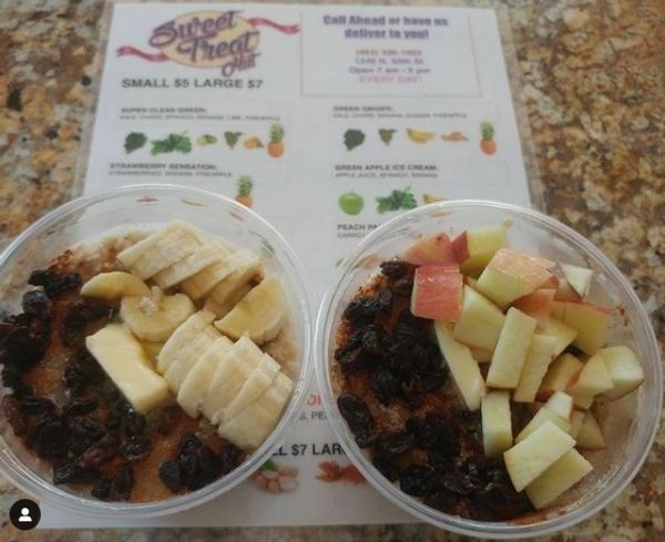 Two bowls of fruit are on a table next to a menu for sweet treats