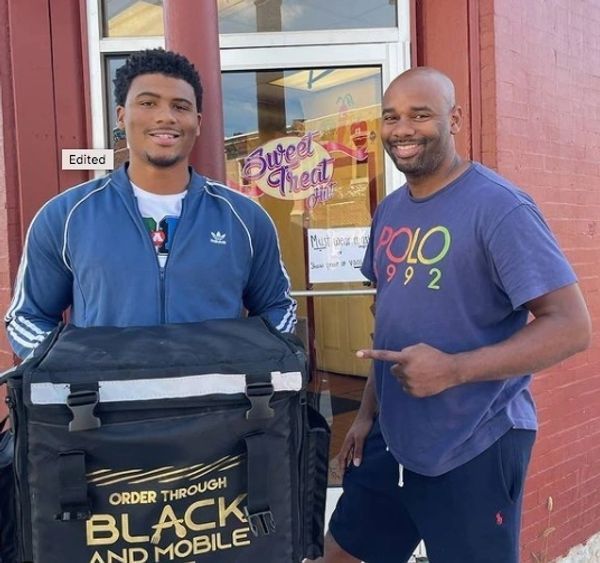 Two men standing in front of a store that says black and mobile