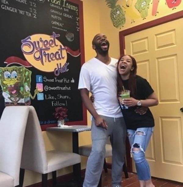 A man and woman standing in front of a sign that says sweet treat hut