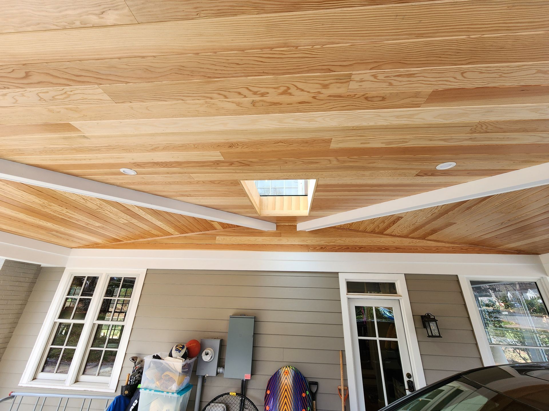Wood ceiling with skylight over a garage entrance; includes white trim, windows, and a gray exterior.