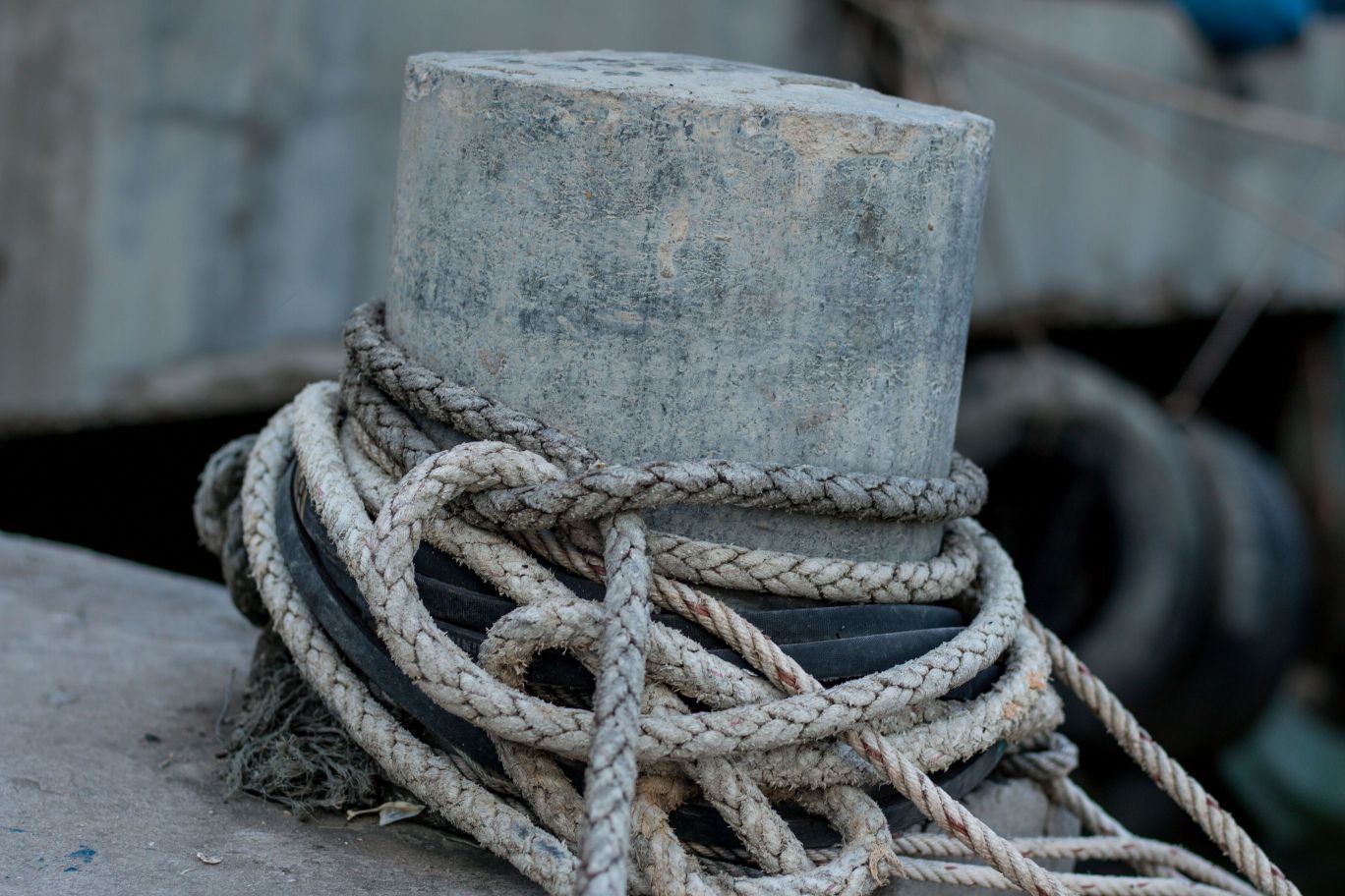 A concrete bollard with ropes tied around it.
