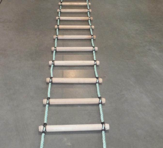 Rope ladder with wooden rungs on a gray floor.