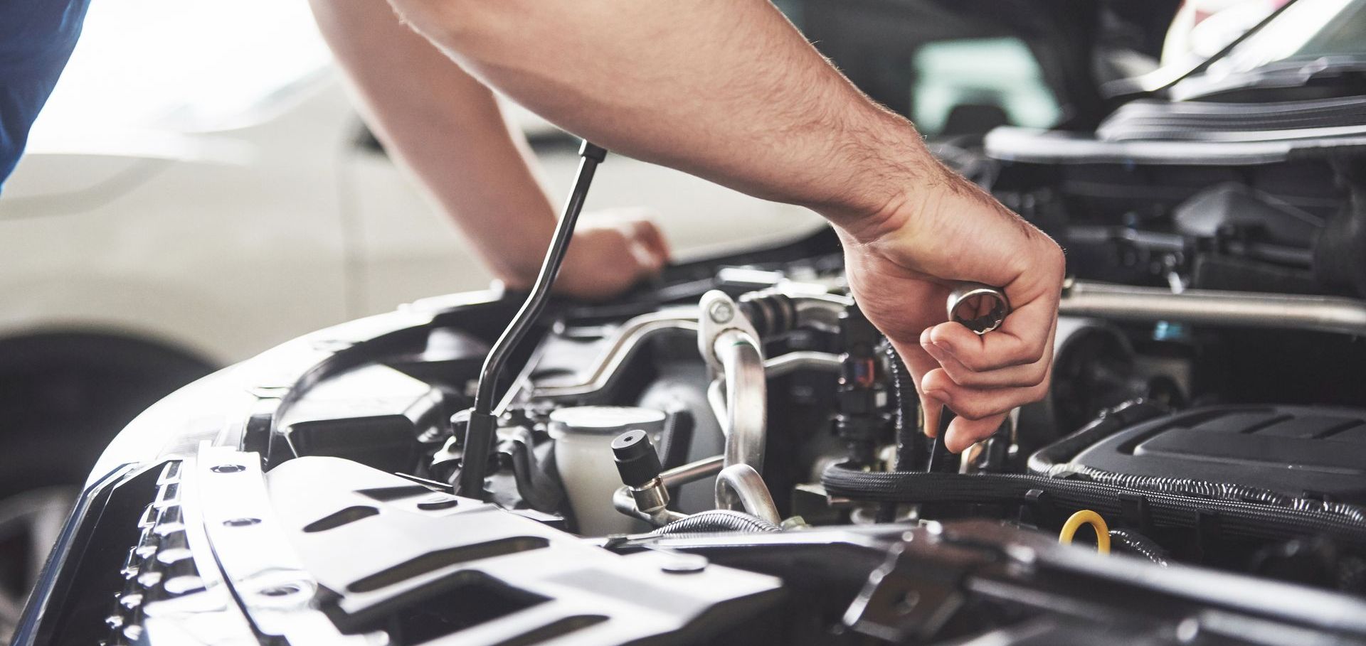Close up hands of unrecognizable mechanic doing car service and maintenance.