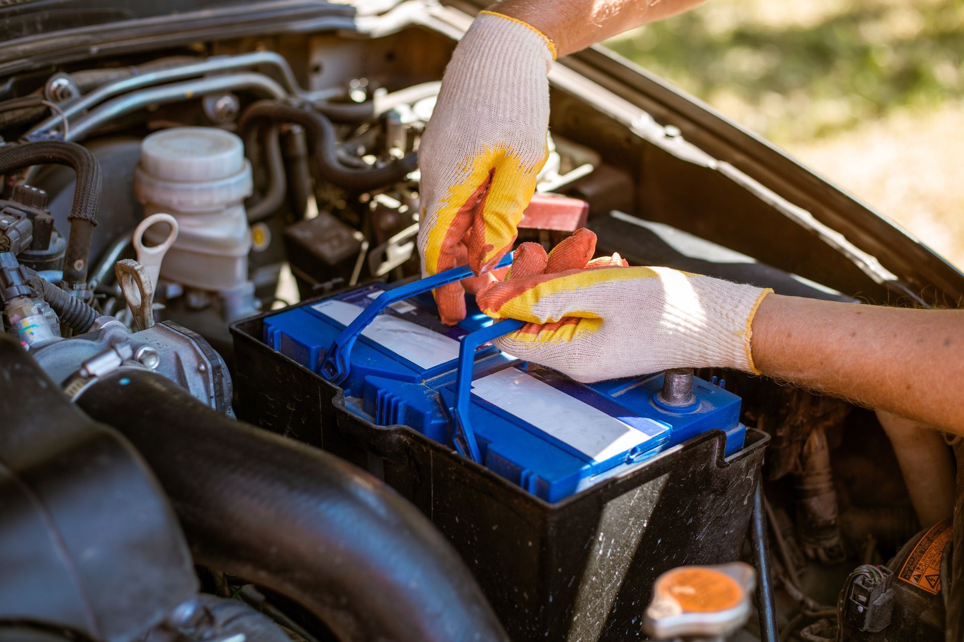 A man removes a battery from under the hood of a car. Battery replacement and repair.
