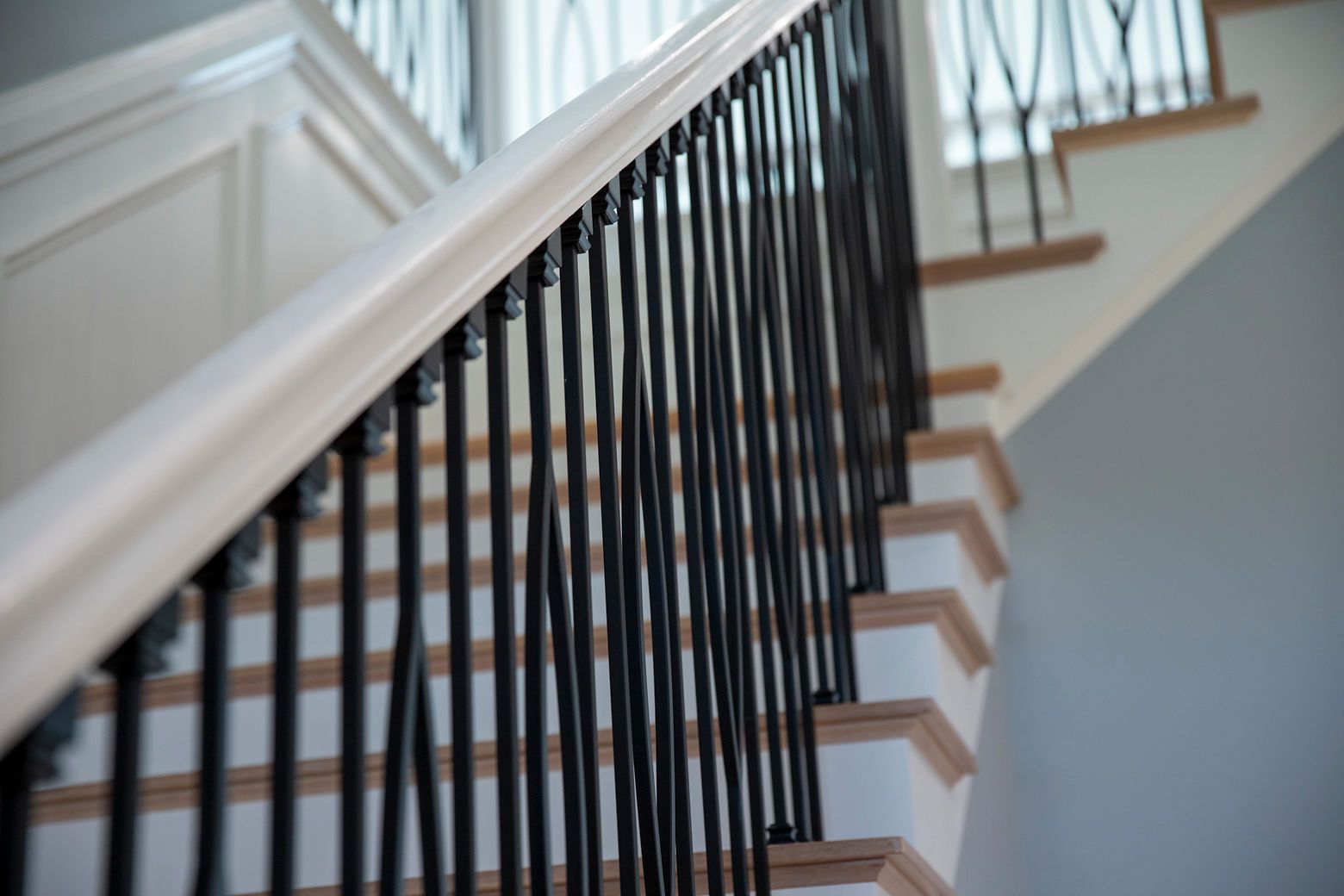 A modern staircase design featuring new carpeting and sleek black spindles.