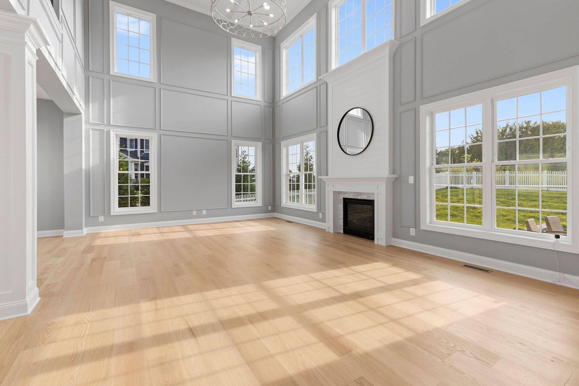 A living room renovation with a fireplace, new hardwood flooring, and stylish wainscoting.