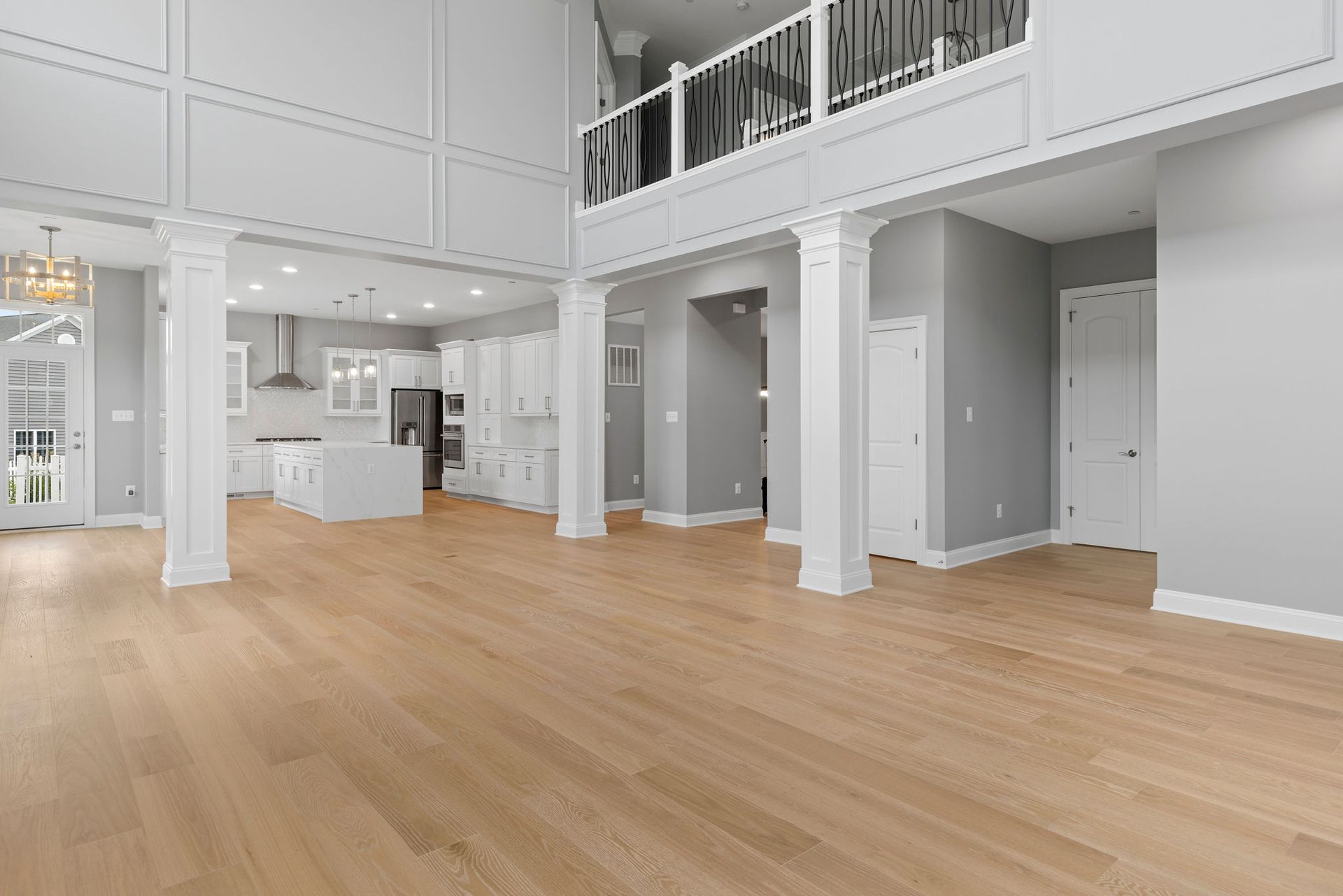 The finished living room and kitchen, showcasing new hardwood flooring, elegant wainscoting, and a modern, complete kitchen remodel.