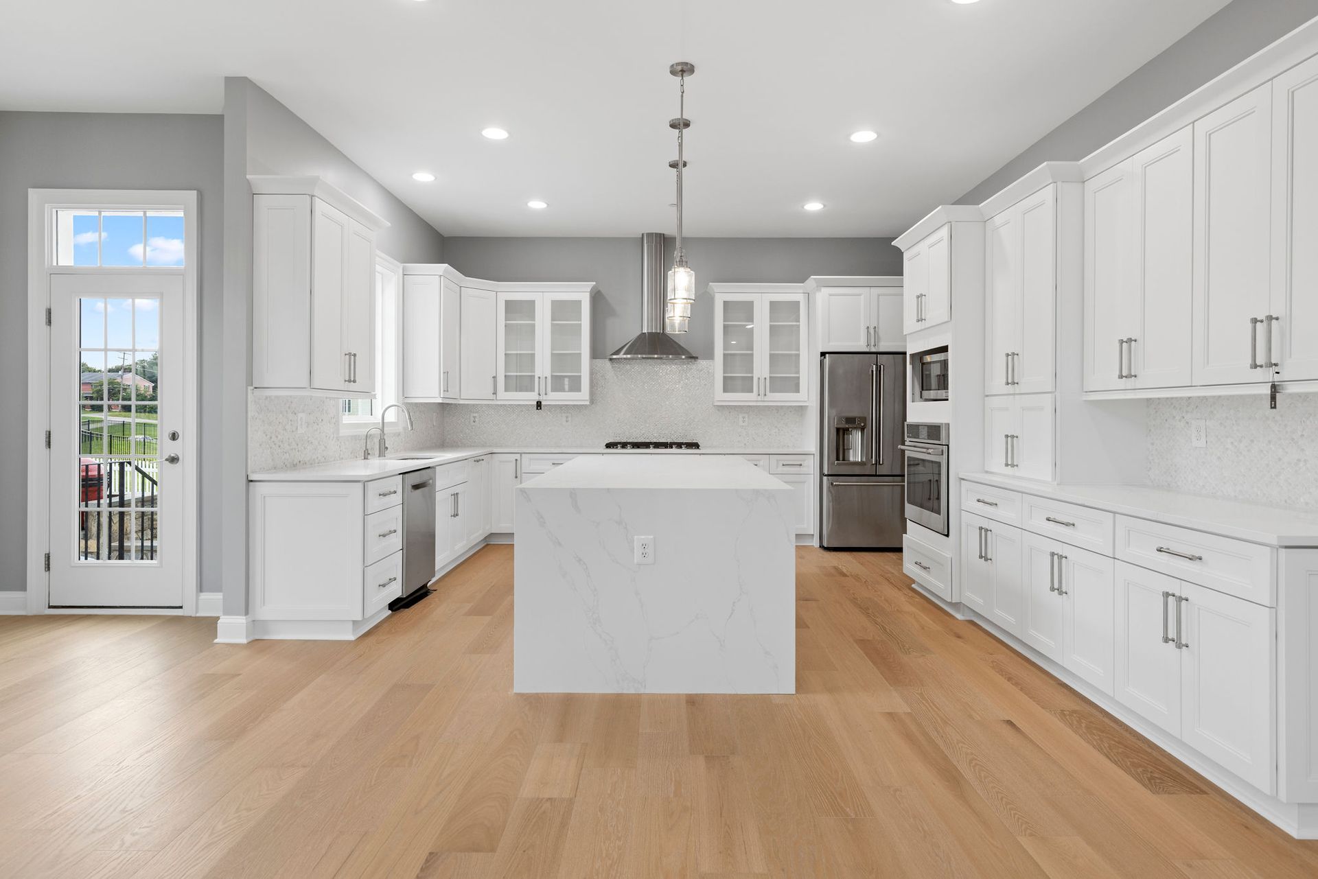 A newly remodeled kitchen with sleek stainless steel appliances, quartz countertops, a subway tile backsplash, and elegant pendant lighting.