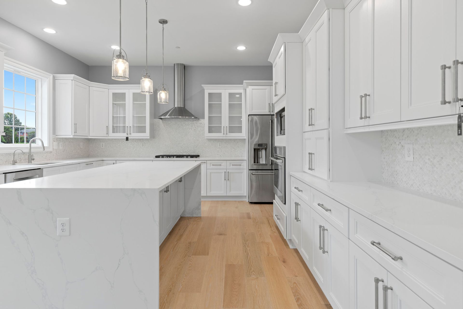 New open-concept living area after a full-home transformation, showcasing new light wood flooring and custom trim.
