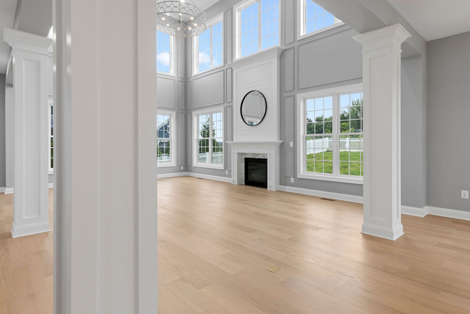 Living room renovation with a fireplace, new hardwood flooring, and stylish wainscoting.