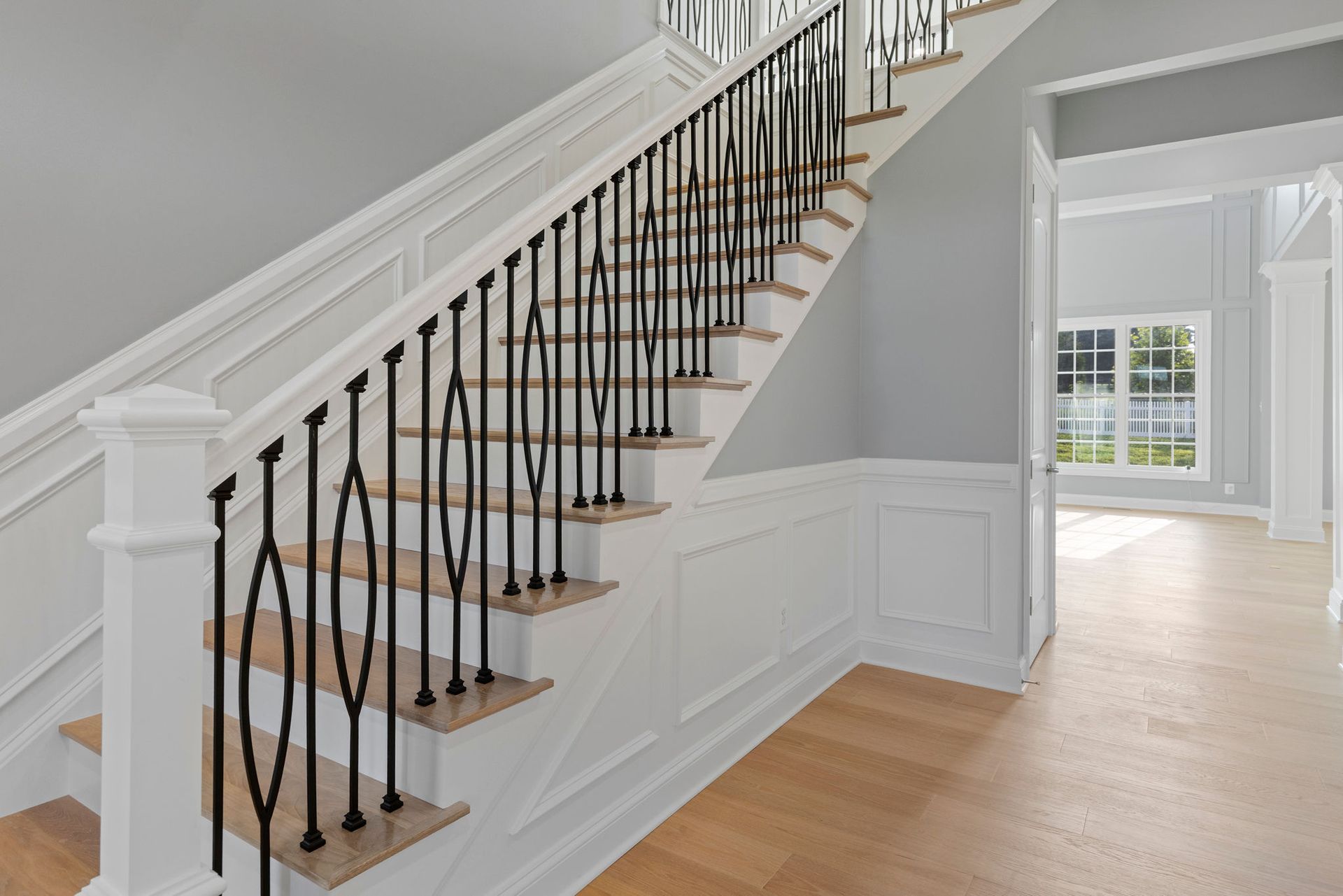 A renovated staircase with a new black metal railing and a white handrail.