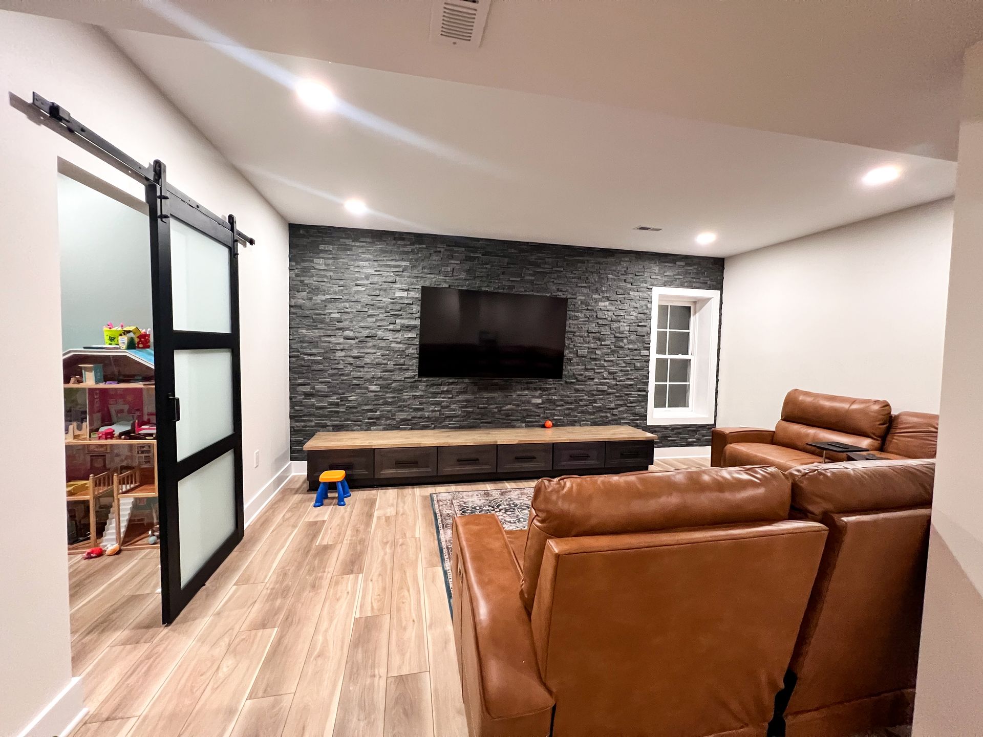 Finished basement living room with black accent wall and TV.