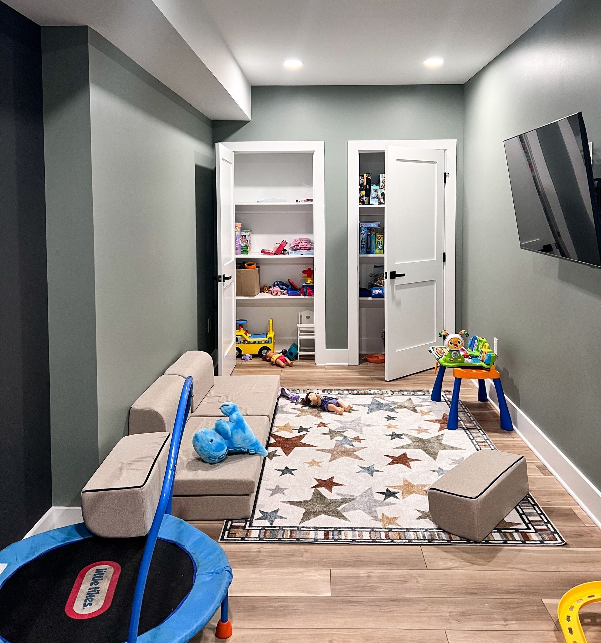 Finished basement playroom with colorful toys, built-in shelving, and a seating area.