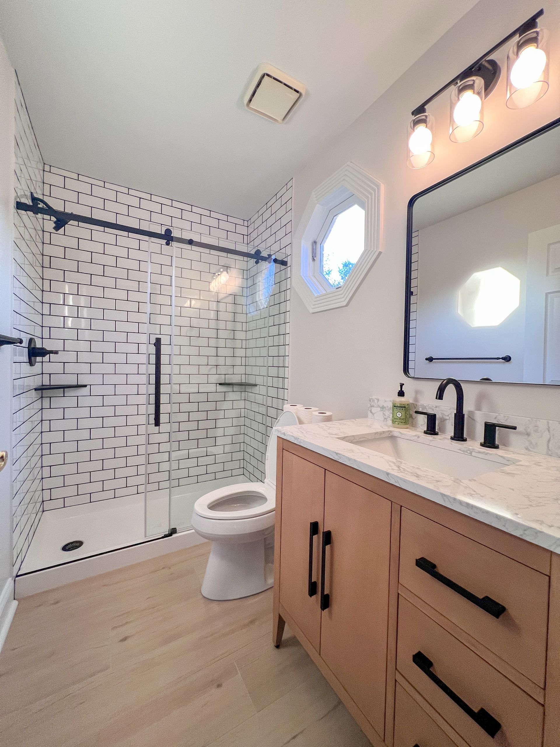 Contemporary bathroom with walk-in shower, white tile, and light wood vanity.