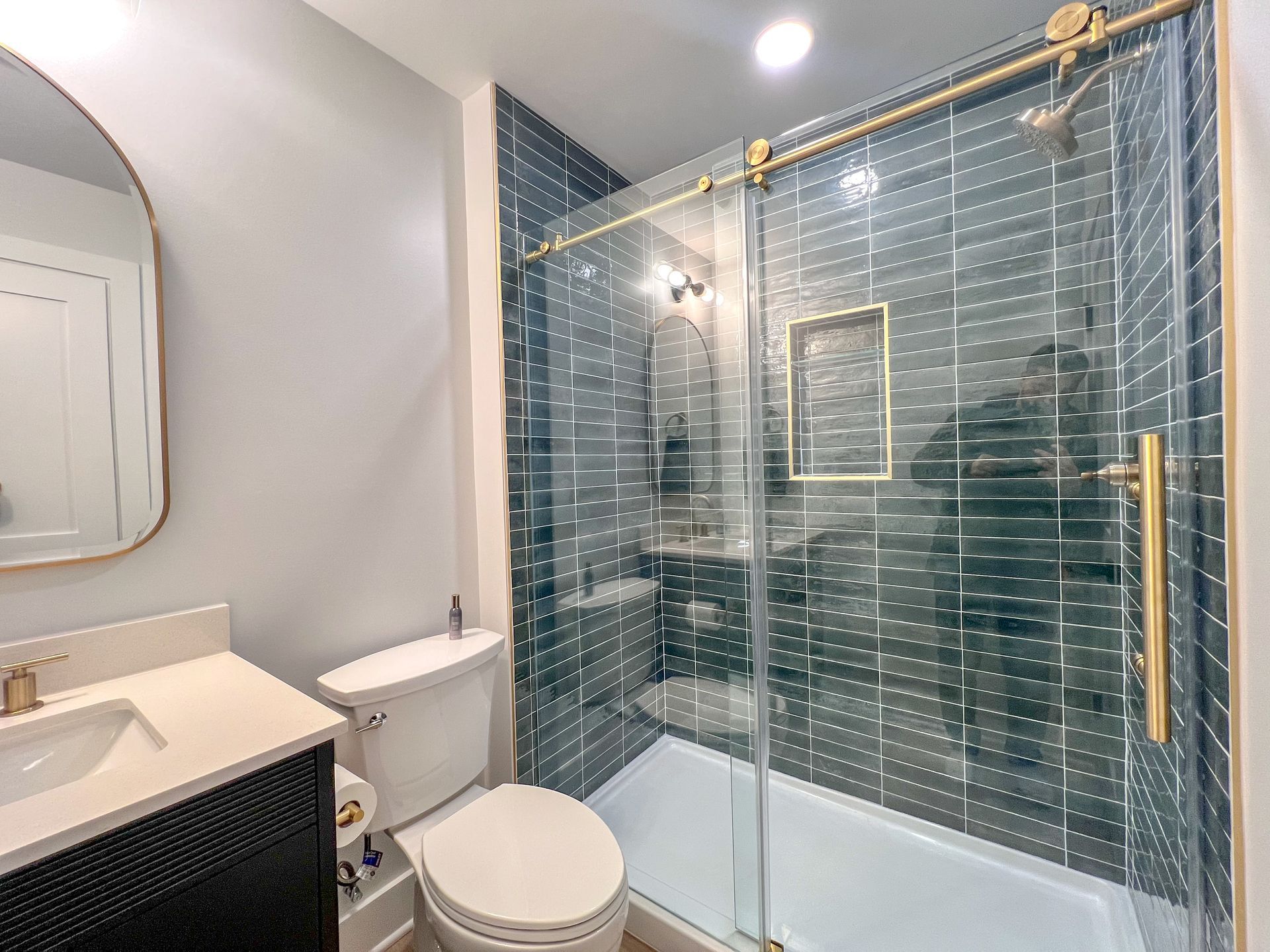 Finished basement bathroom with glass shower and dark vanity.