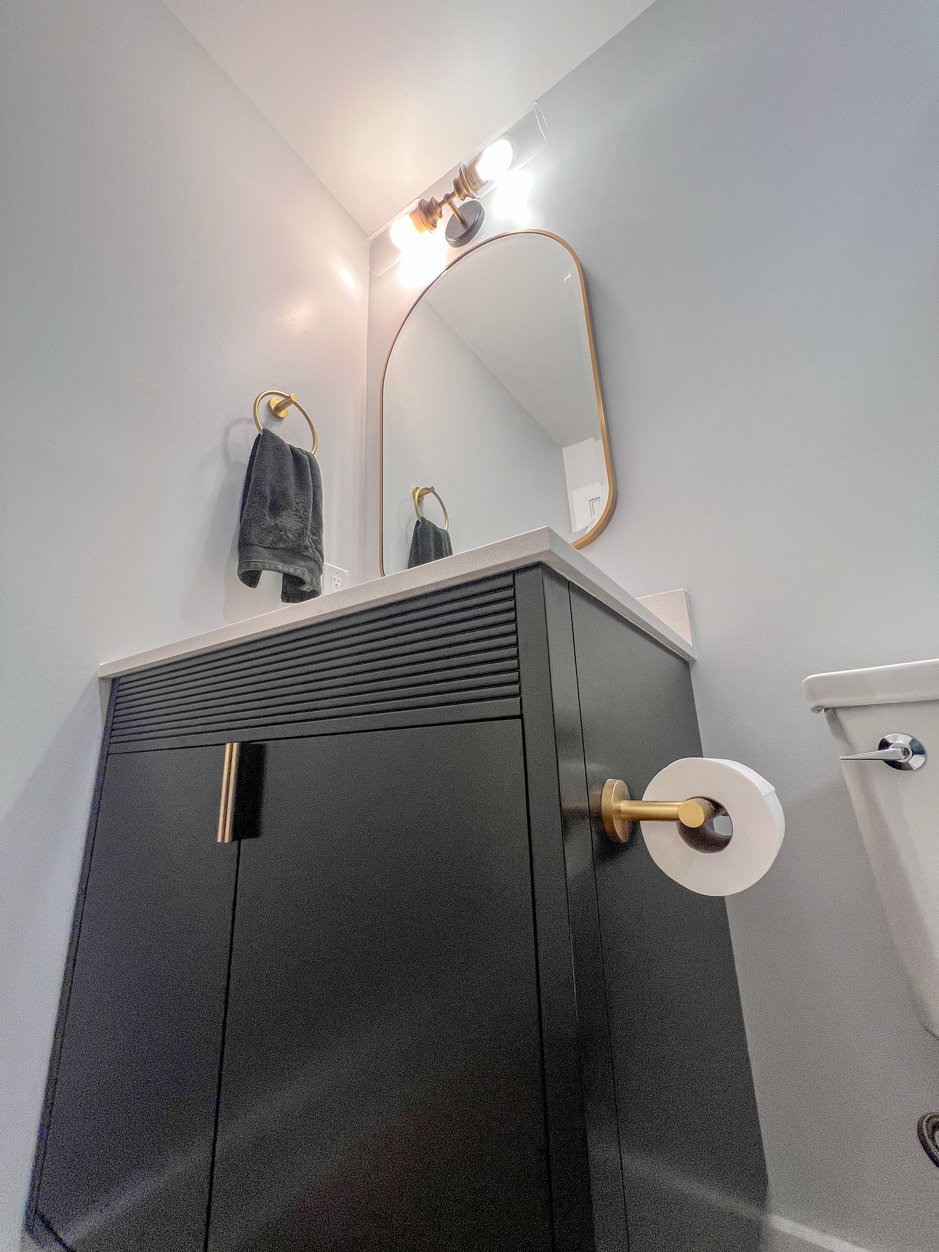 Dark vanity cabinet with white countertop and vessel sink.