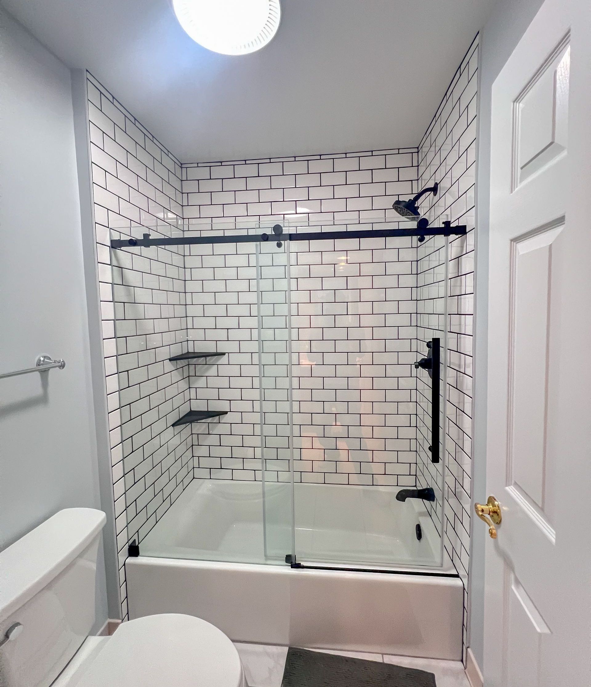 Modern bathroom design with walk-in shower, white tile, and light wood vanity.