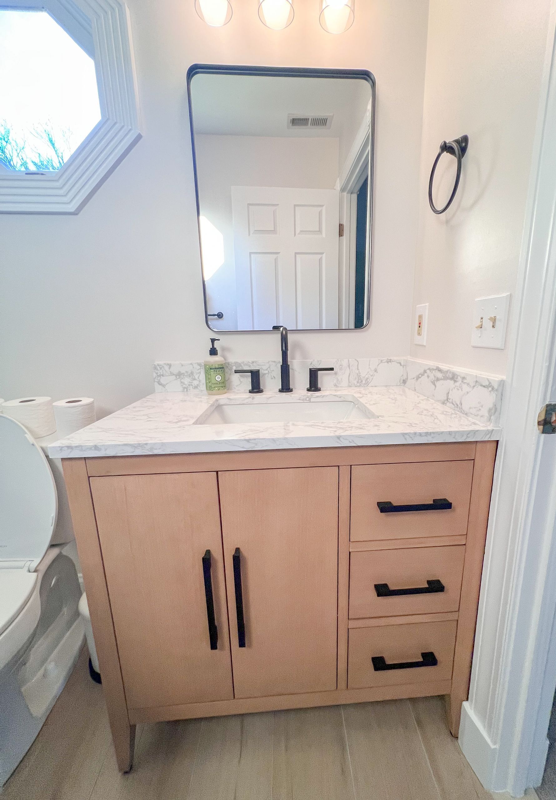 Updated bathroom with walk-in shower, black hardware, and light wood vanity.