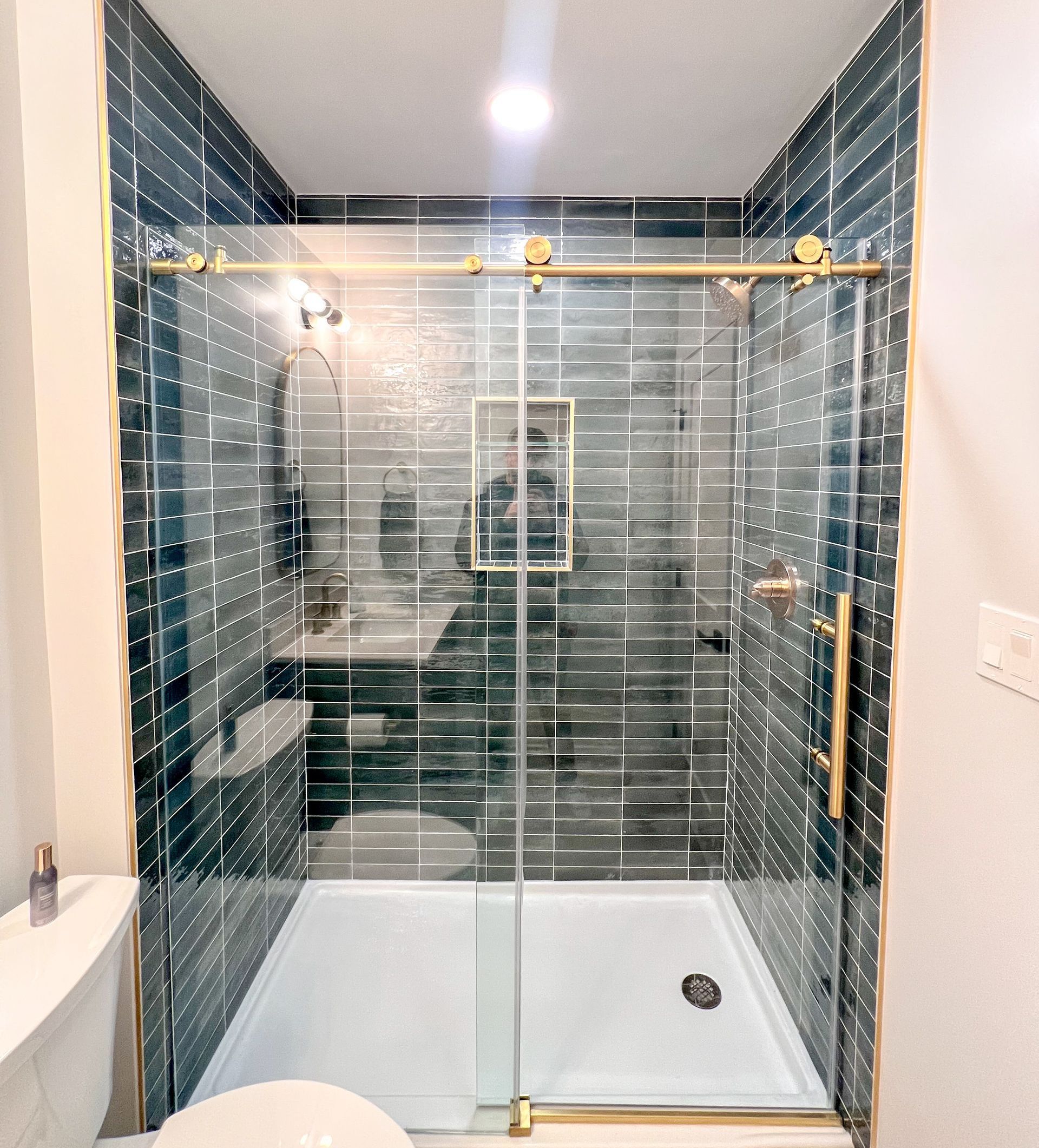 Modern bathroom with blue tile and gold accents.