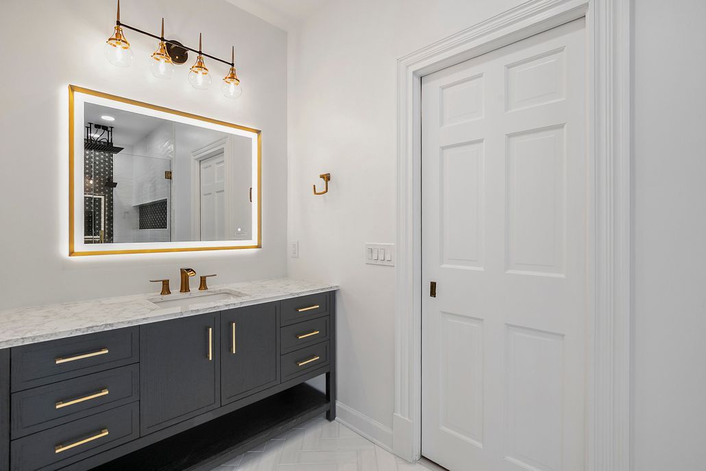 Close-up of the new black vanity with a quartz countertop, gold hardware, and a modern LED-lit mirror.