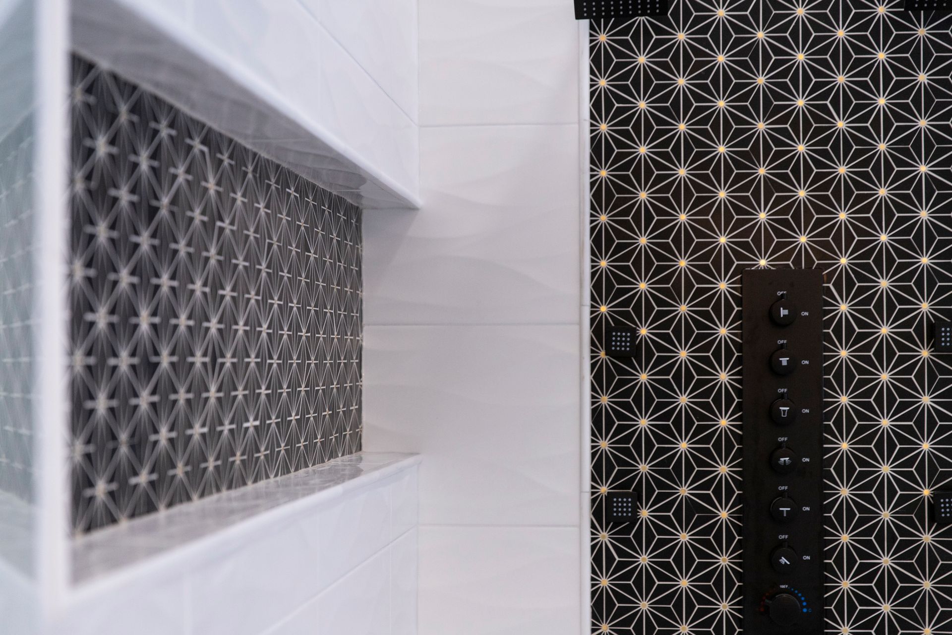 A close-up of the custom-sized shower niche with a unique black and white geometric tile, and the new black shower controls.