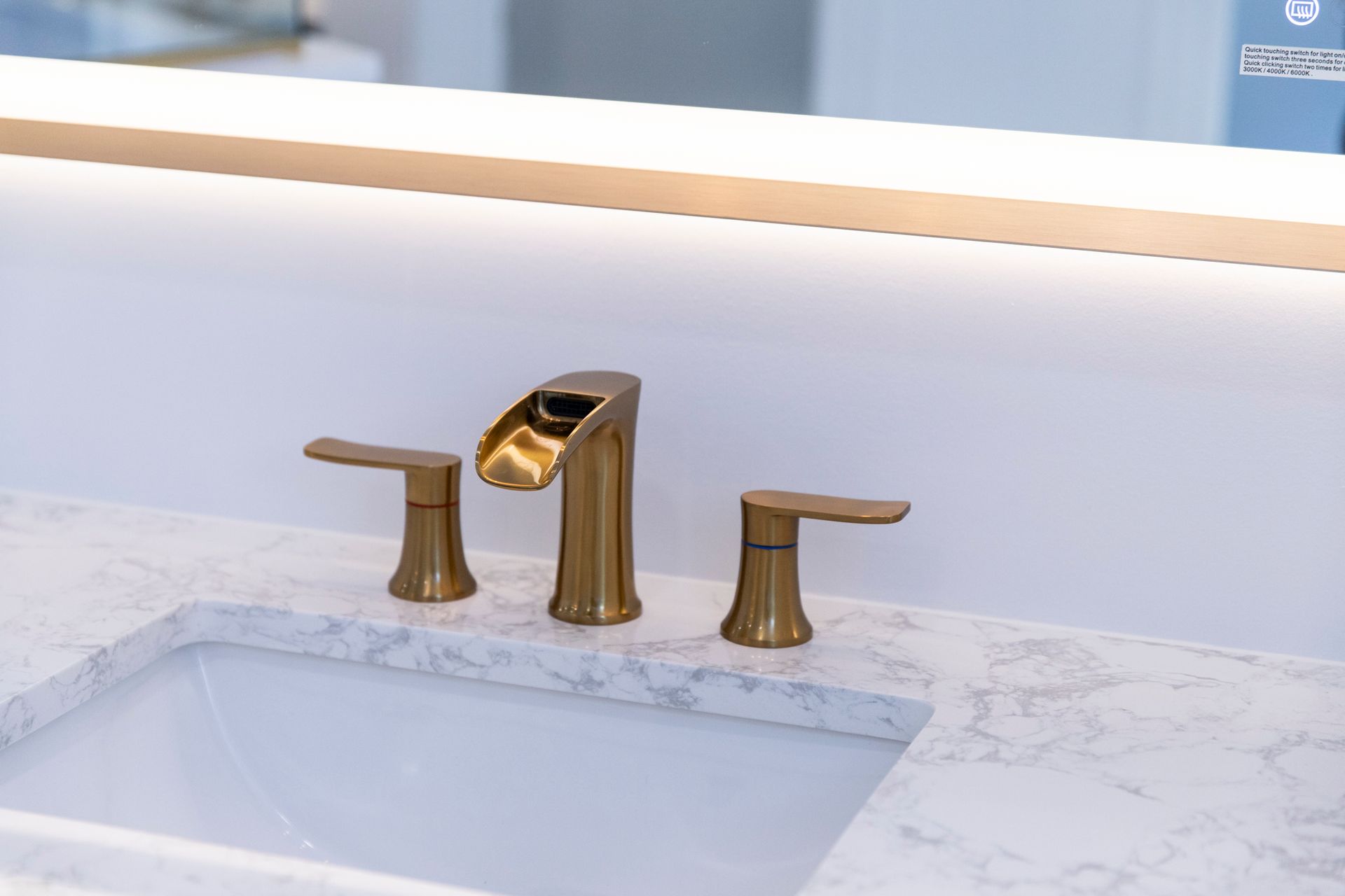 A detailed view of the new gold faucet and sink, with a focus on the modern design and illuminated mirror.