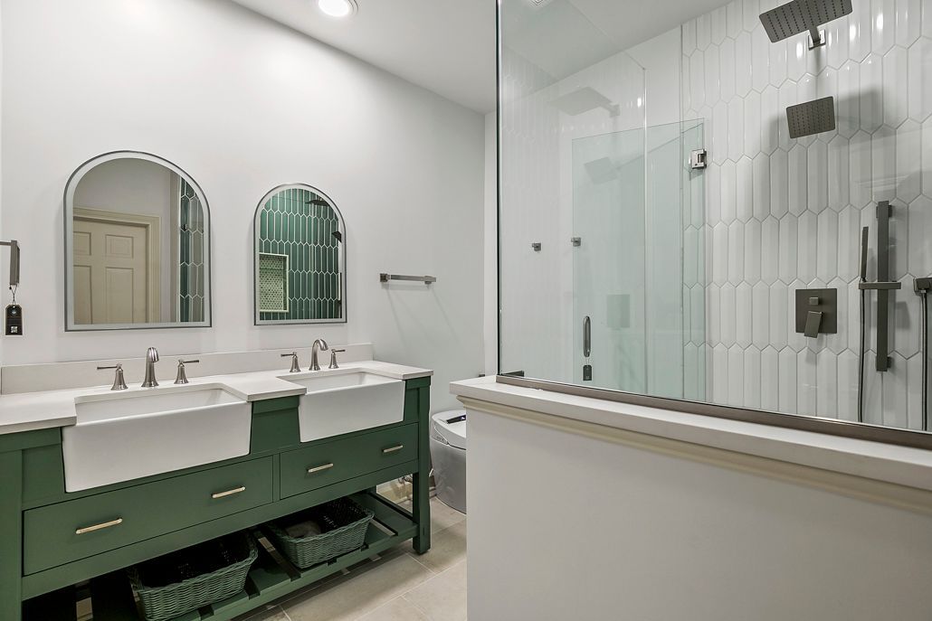 Complete view of a newly renovated Cockeysville bathroom, with a stylish green double vanity, a modern walk-in shower with glass doors, and designer tile work.