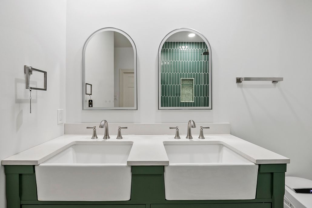 Custom green double vanity with two large farmhouse sinks and arched mirrors, showcasing a full bathroom remodel in Cockeysville.