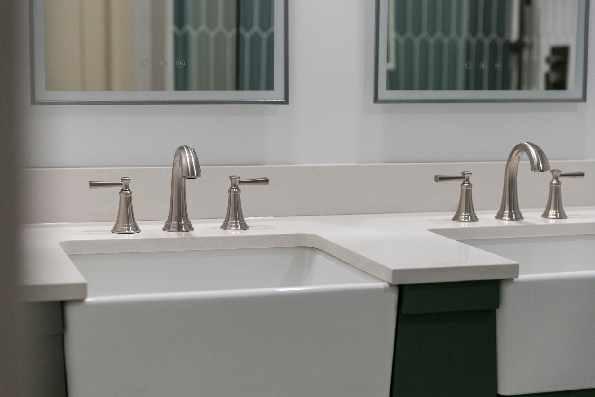 Close-up of modern brushed nickel faucets and hardware on a double sink vanity.