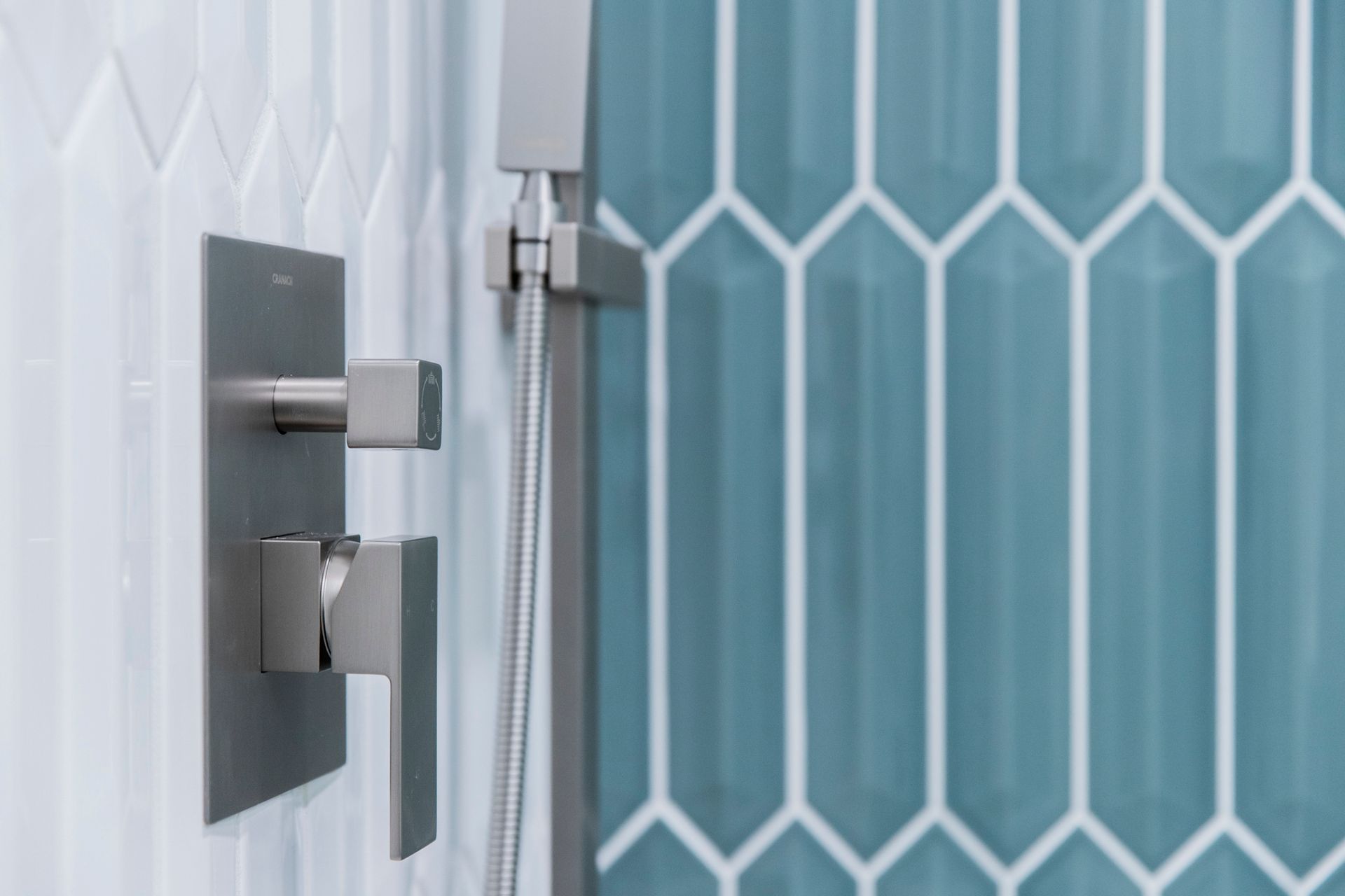 Brushed nickel shower hardware against a stylish blue-green and white vertical tile accent wall.