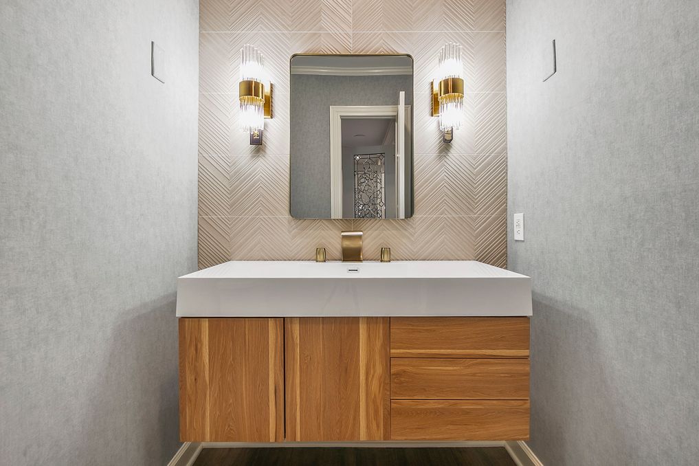 A renovated, modern powder room featuring a floating wood vanity, large mirror,