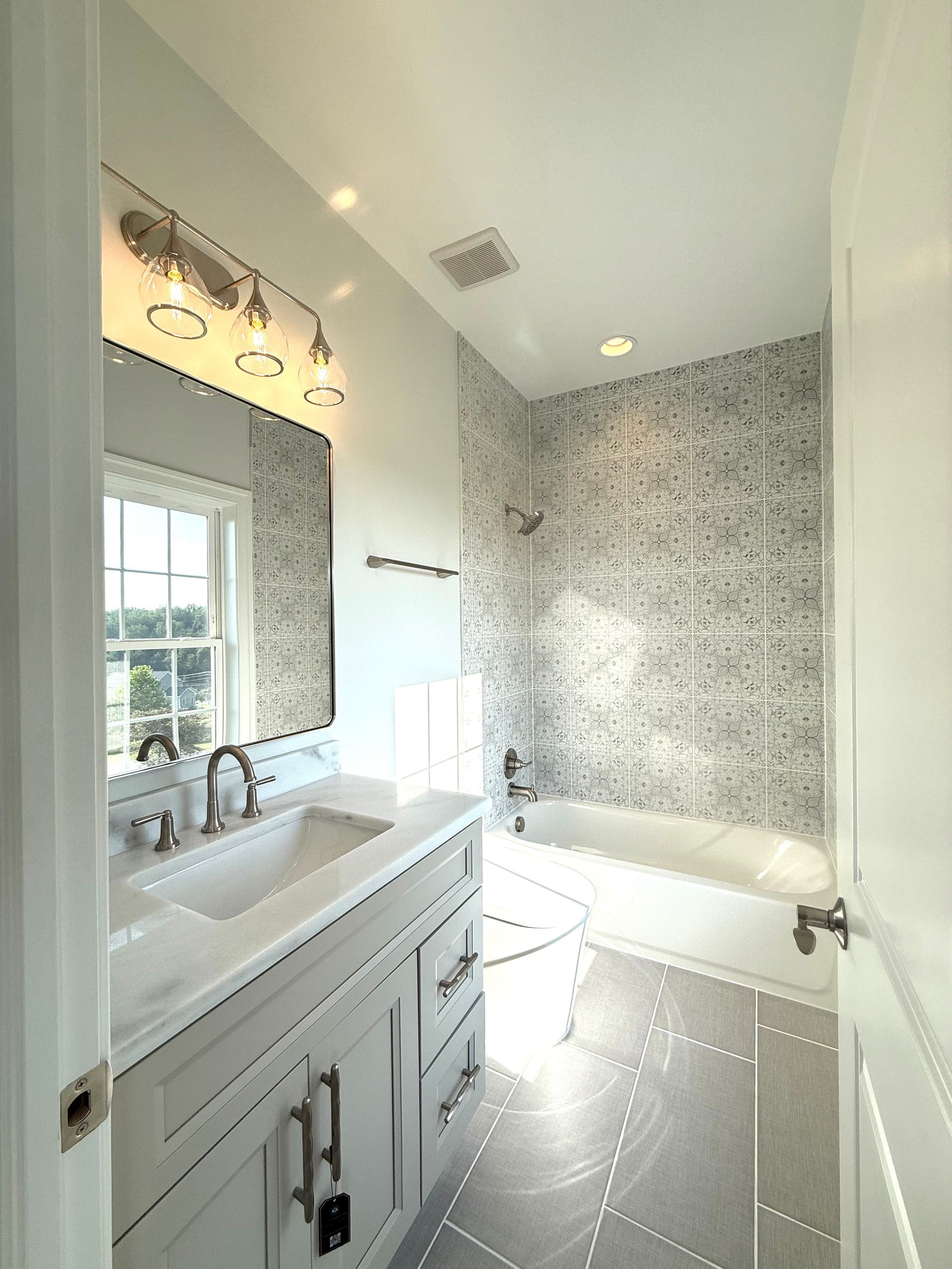 Modern hall bathroom vanity with a white countertop, brushed nickel faucet, and a large mirror in a Westminster home.