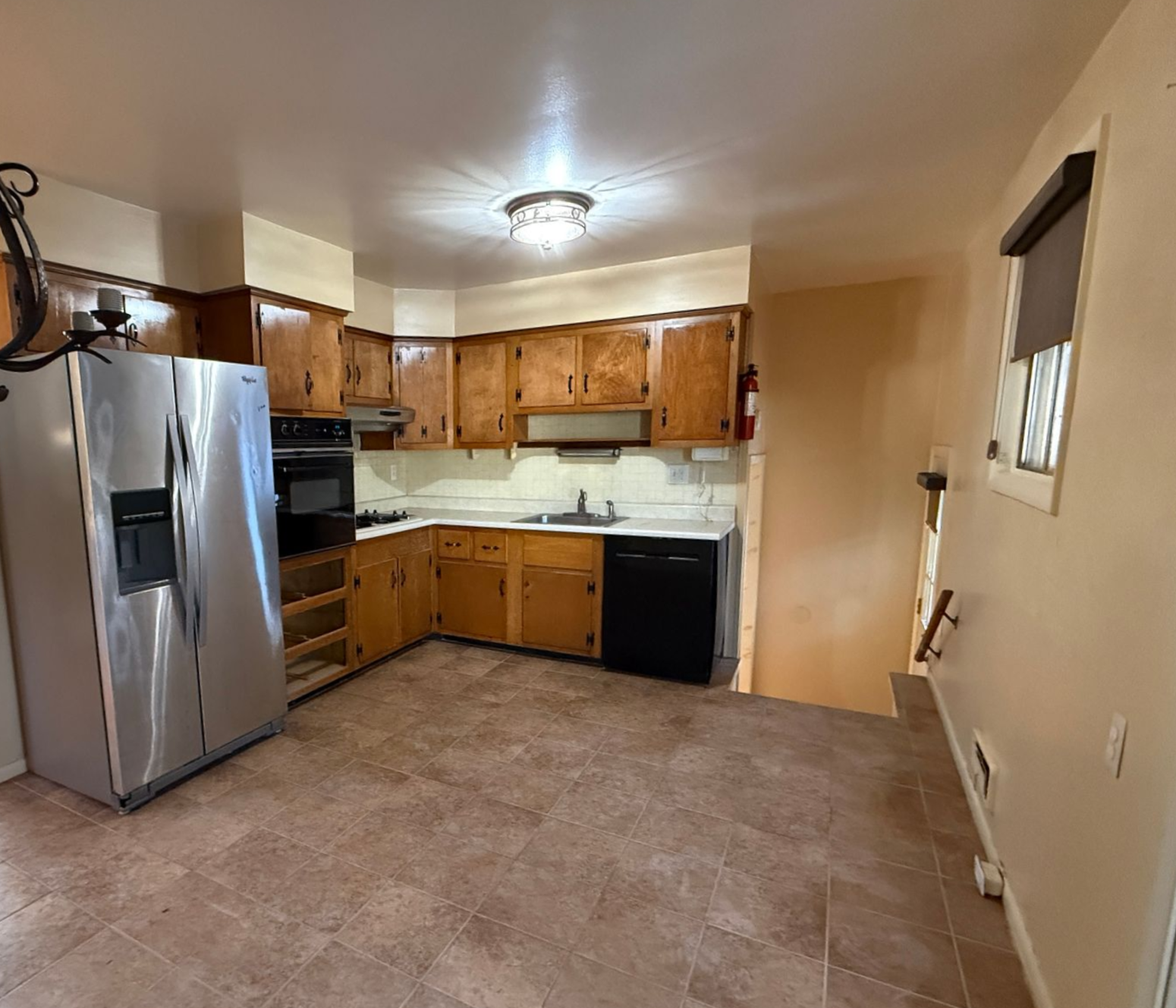 Original kitchen space featuring dark bulkheads, limited wall cabinetry, and older appliances.