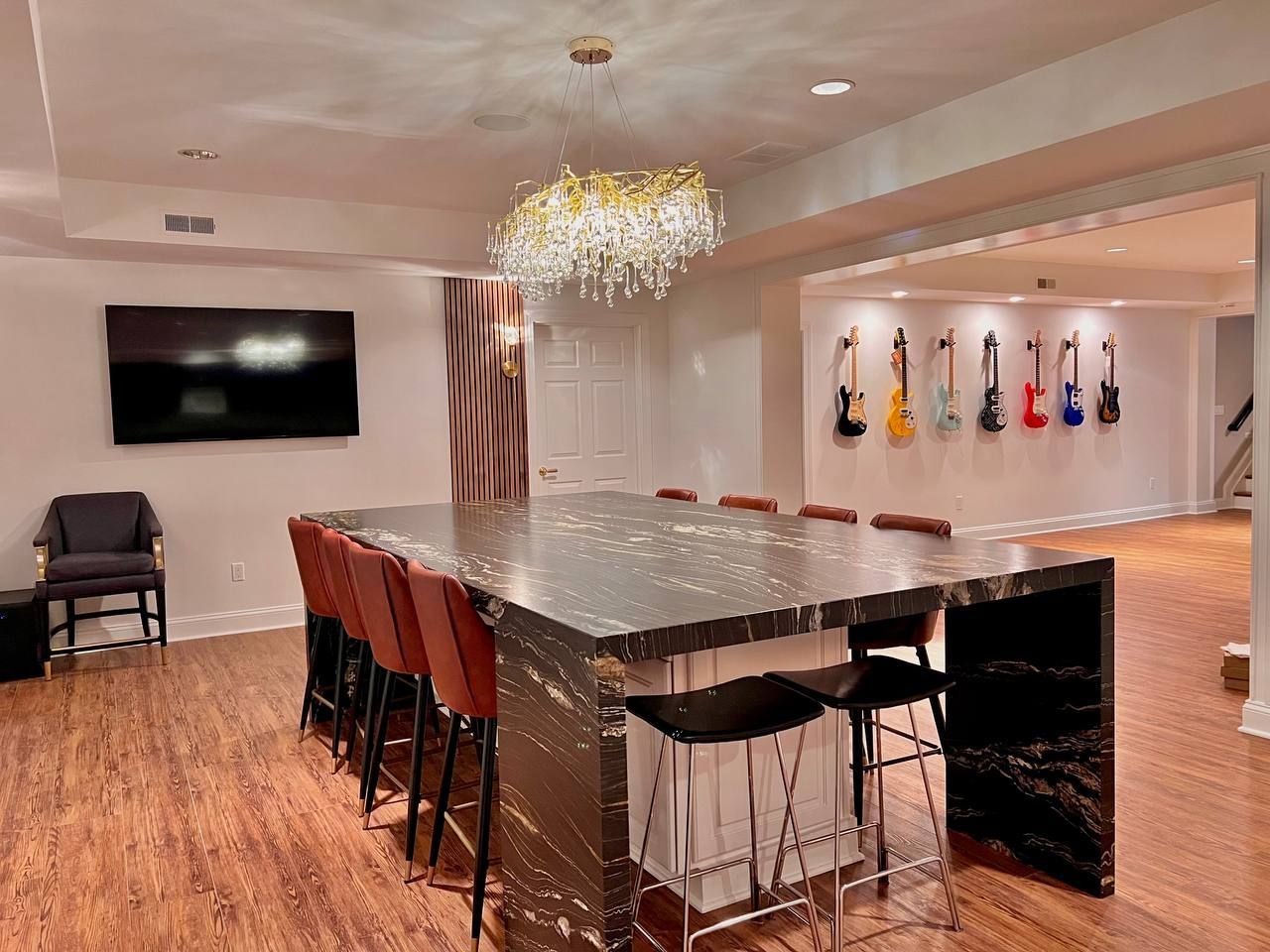  Contemporary finished basement in Bel Air, MD, featuring a large island with seating, a modern kitchenette, and a dining area.