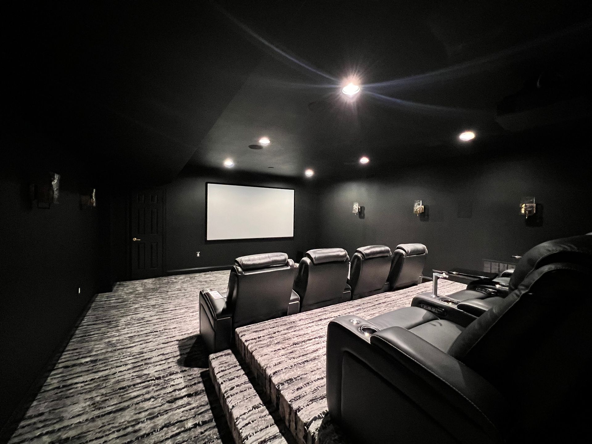 Finished basement home theater with tiered seating and a projector screen.