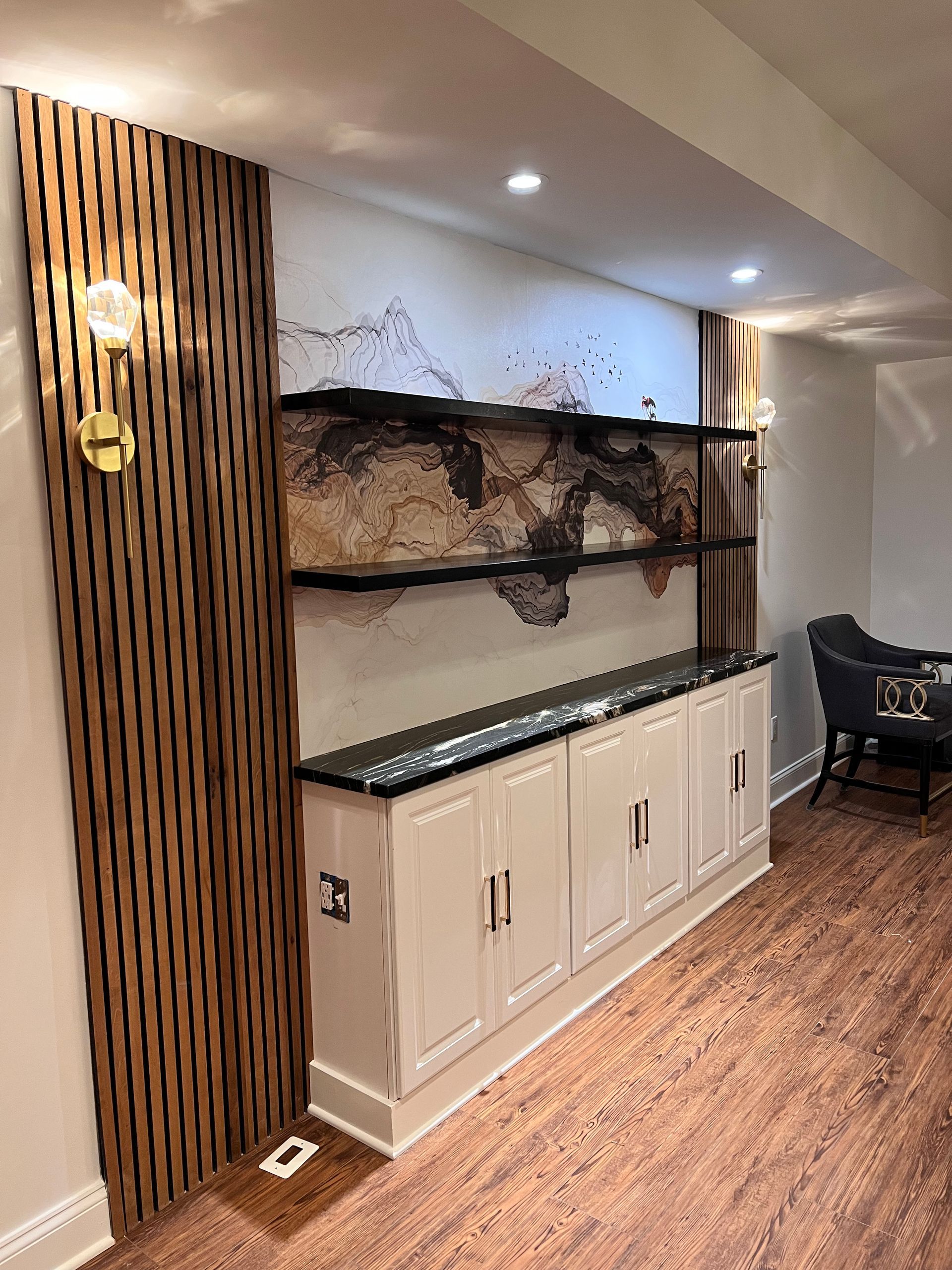 Finished basement bar area with white cabinets, black countertop, and wood slat wall panels in Greater Baltimore, MD