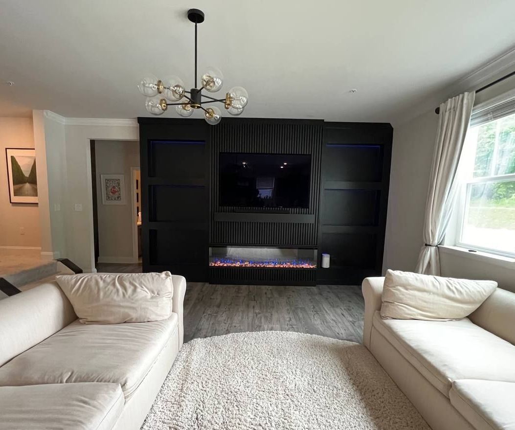 Custom-built black media wall with electric fireplace and blue LED lighting in a Bel Air home.