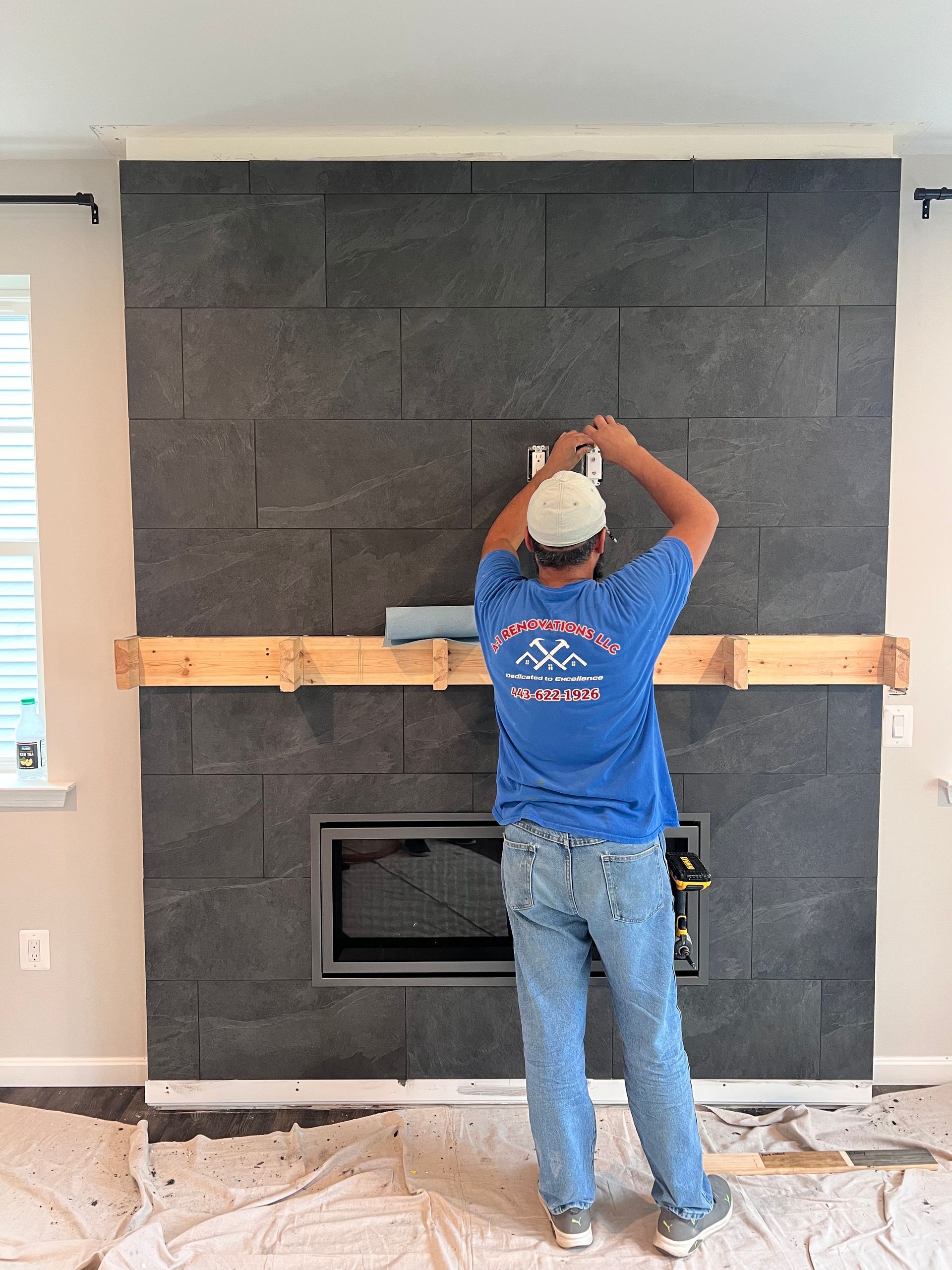 A carpenter working on a custom fireplace surround, with the mantel installation in progress in Greater Baltimore, MD