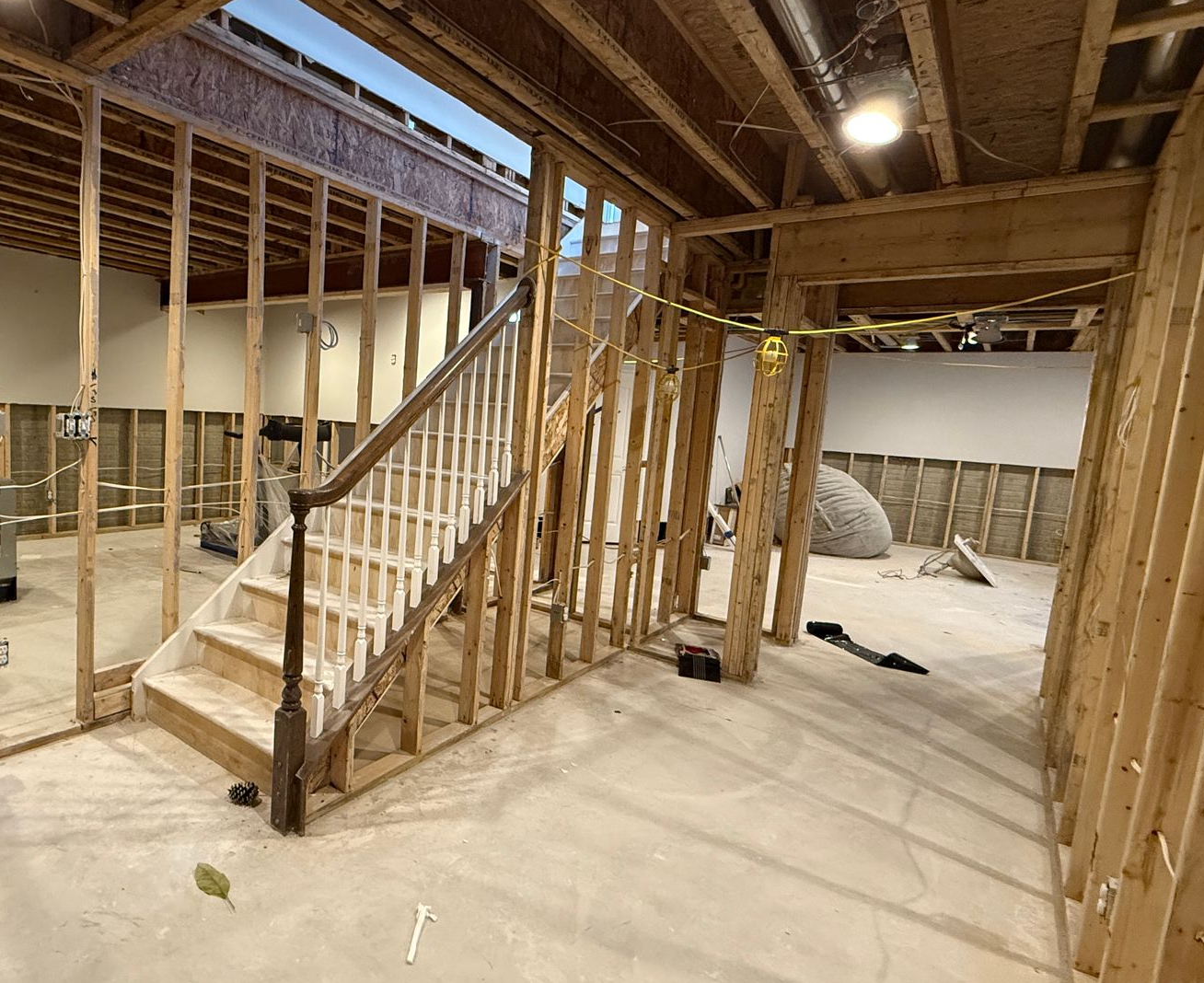 A basement during the renovation phase, with exposed walls and a treadmill covered in plastic.