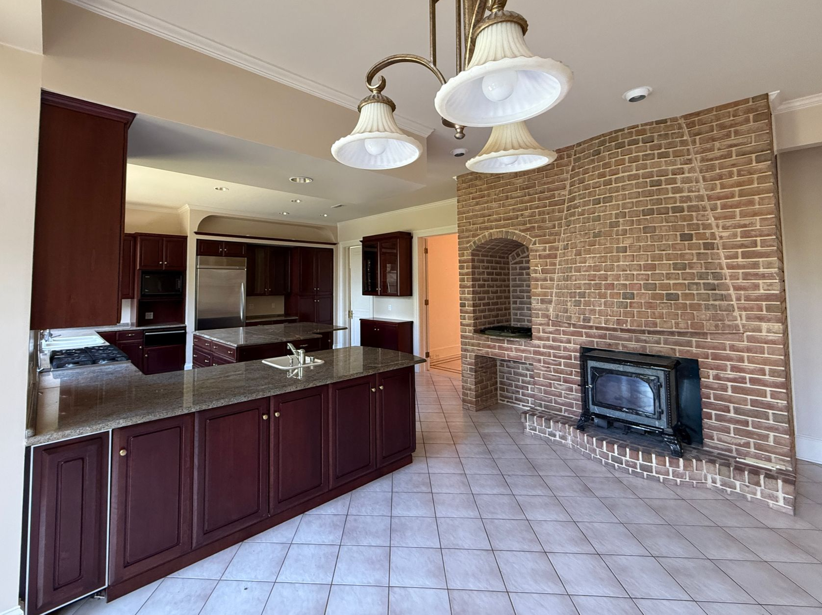 A stylish kitchen featuring light-colored custom cabinetry, stainless steel appliances, and an intricate tile backsplash.
