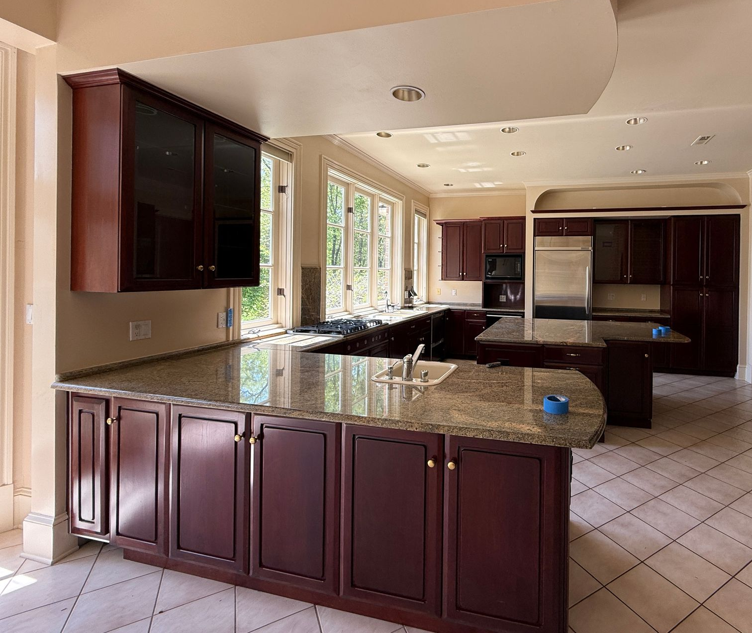 An image capturing the old kitchen’s layout, showing the original refrigerator, dark wood cabinets, and a narrow hallway.