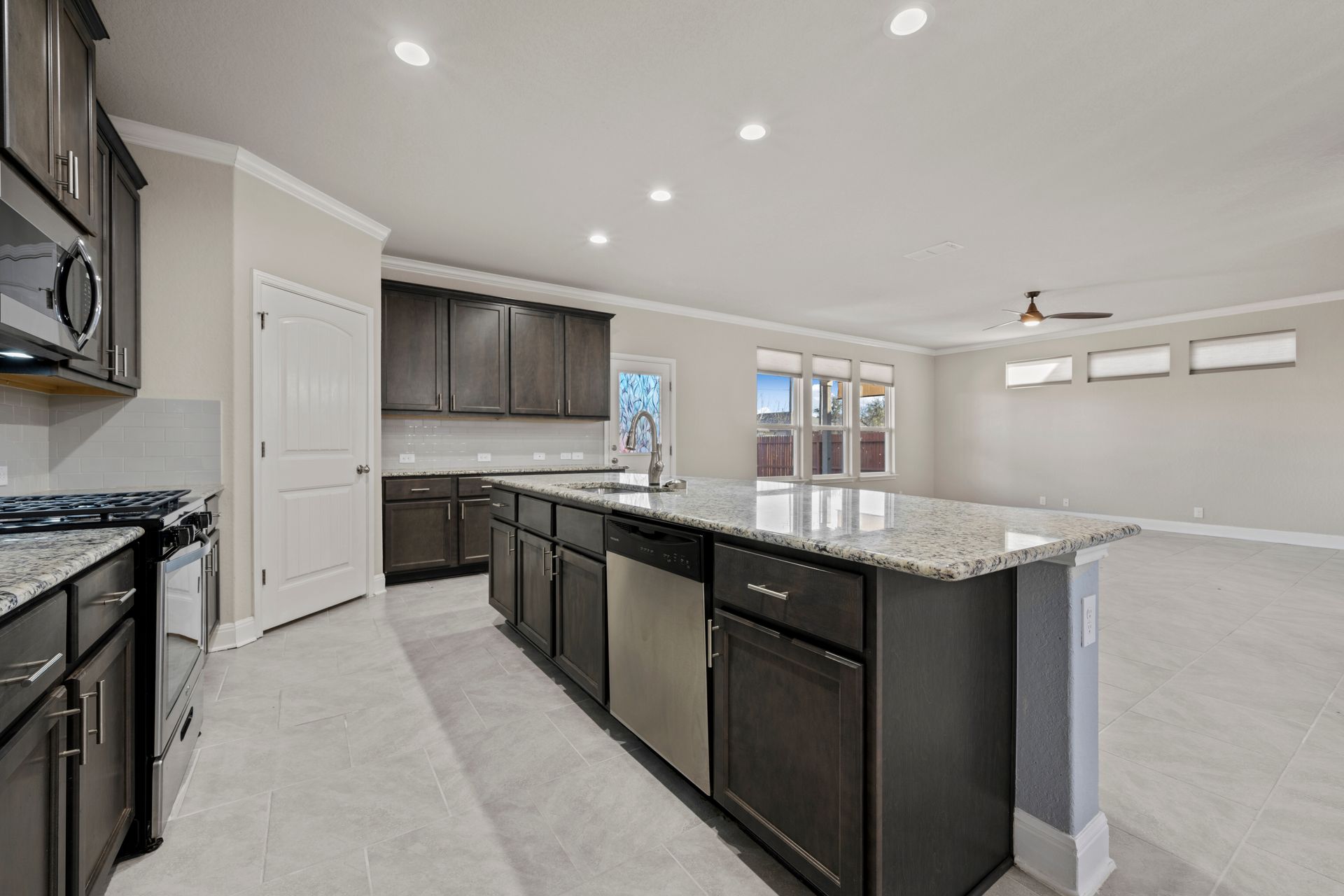 Transitional dark cabinet kitchen in Columbia, Maryland, with shaker cabinets, granite countertops, a spacious island with seating, and stainless steel appliances.