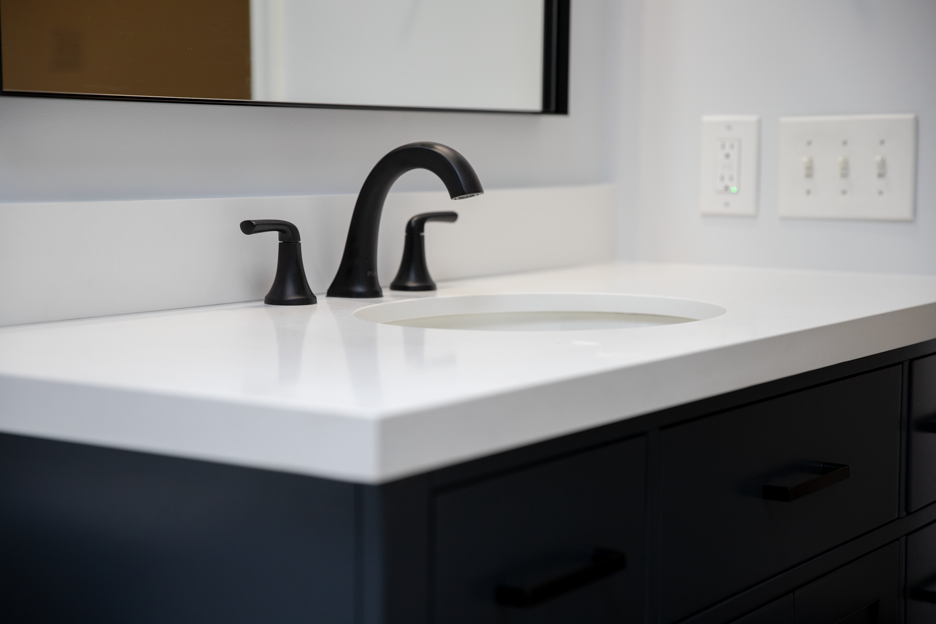 Modern matte black faucet and white countertop on a new bathroom vanity.