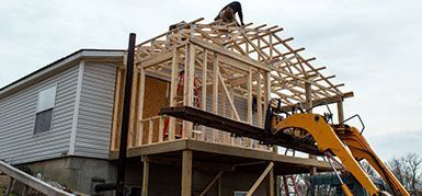 A house is being built with a forklift attached to it.
