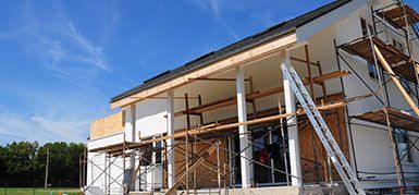 A house is being built with scaffolding and a ladder.