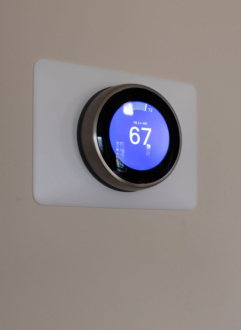 Round blue thermostat mounted on a white wall, displaying 67 degrees.